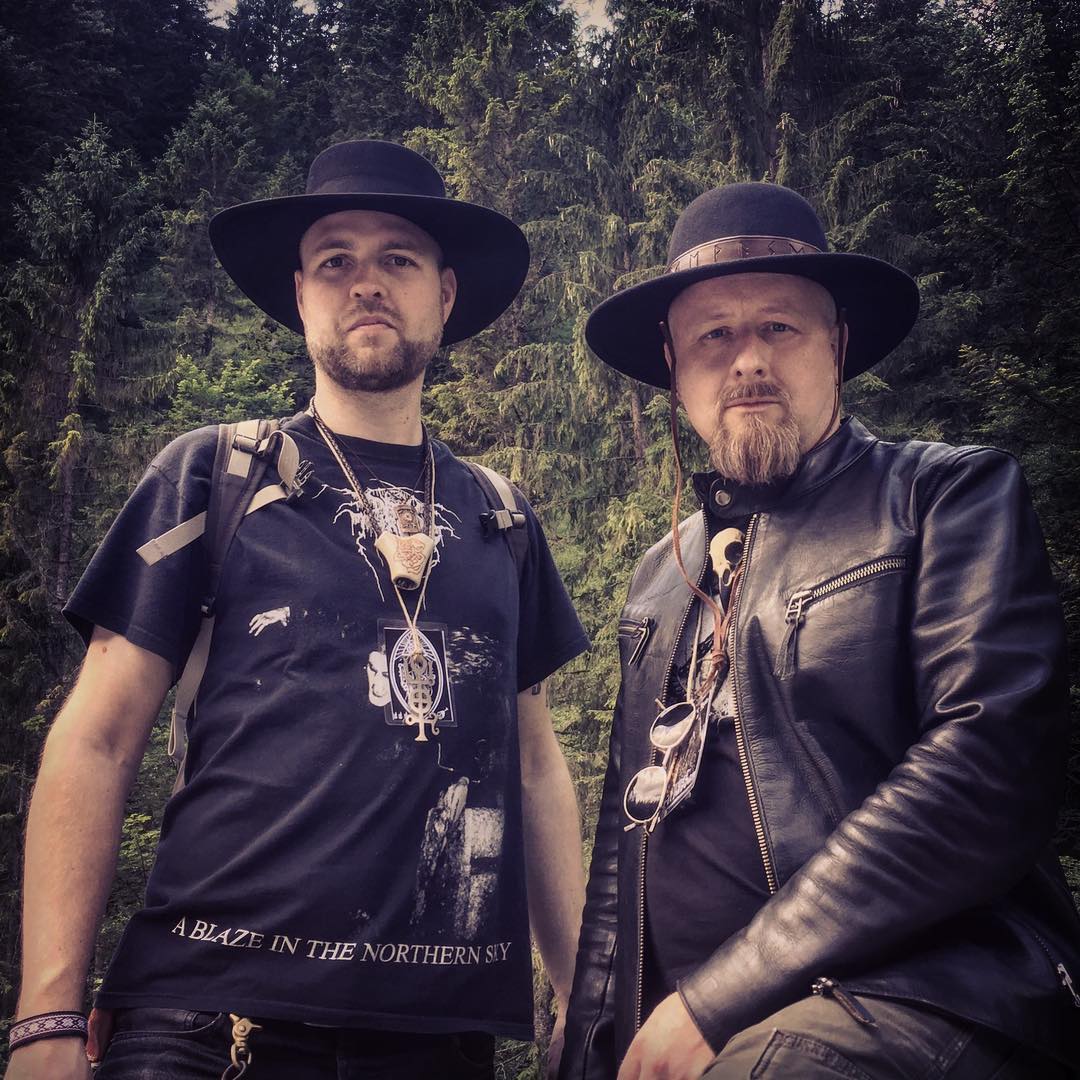 Two stylish bearded men wearing hats and a raven skull necklace made by Raven Ranch Studio.