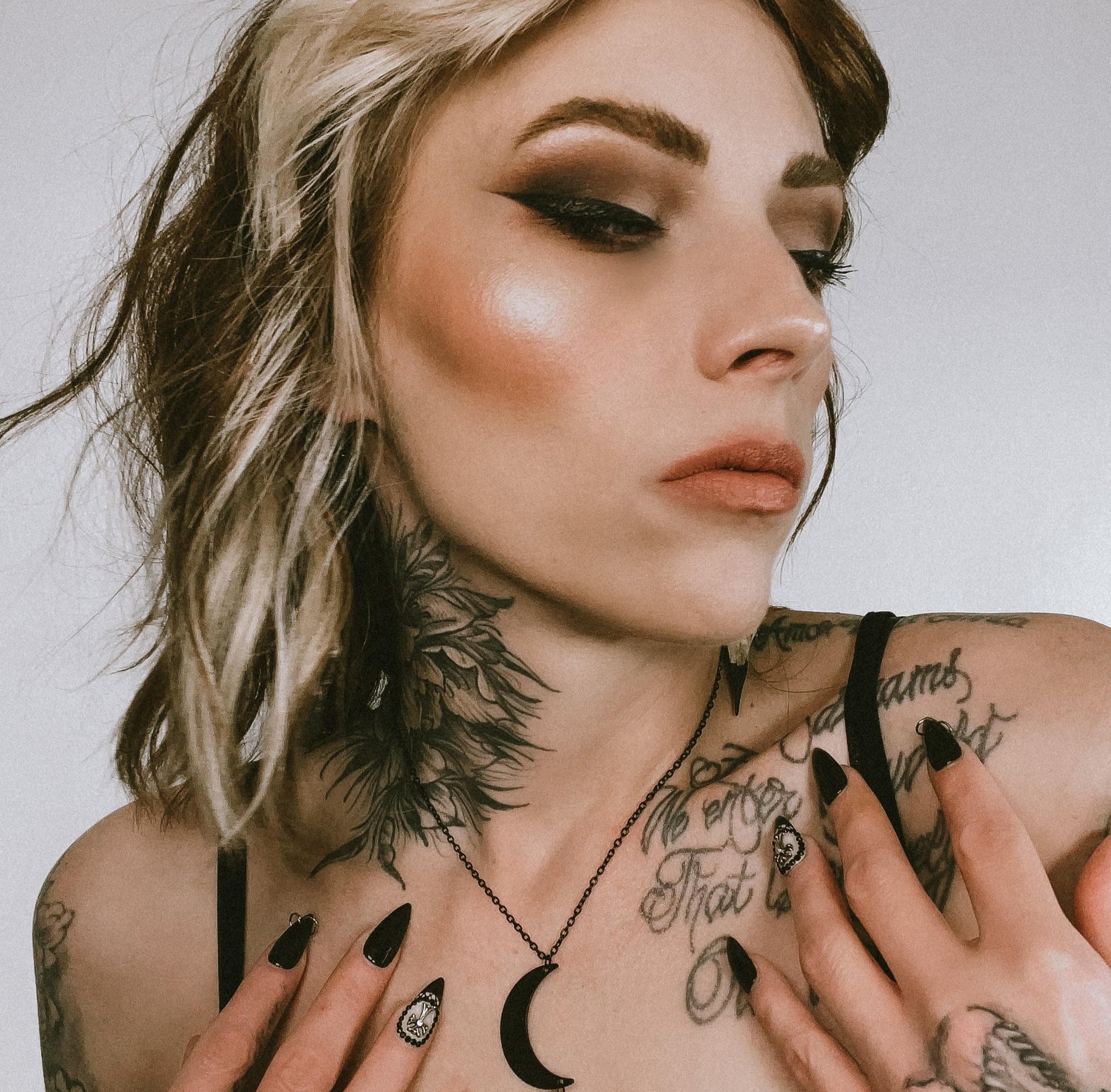 Crescent moon raven skull necklace worn by bird skull jewelry model with tattoos and gothic style clothing