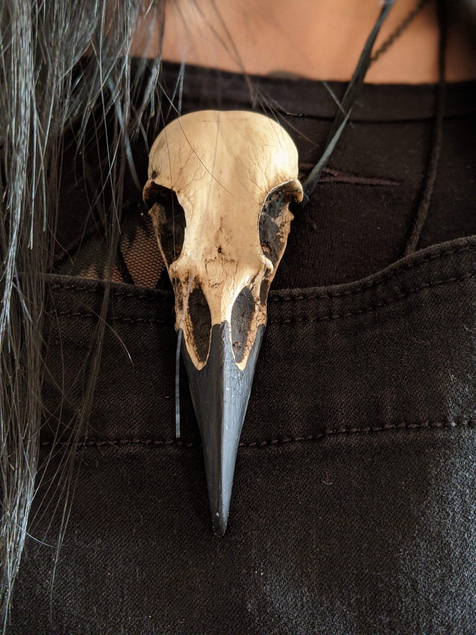 Dirty creepy raven bone jewelry pendant bird skull necklace close up front view.