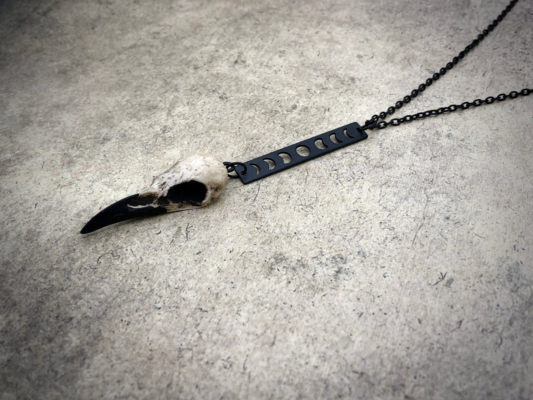 left view of Moon phase vertical bar charm pendant and bone jewelry mini resin raven bird skull dangle pendant.