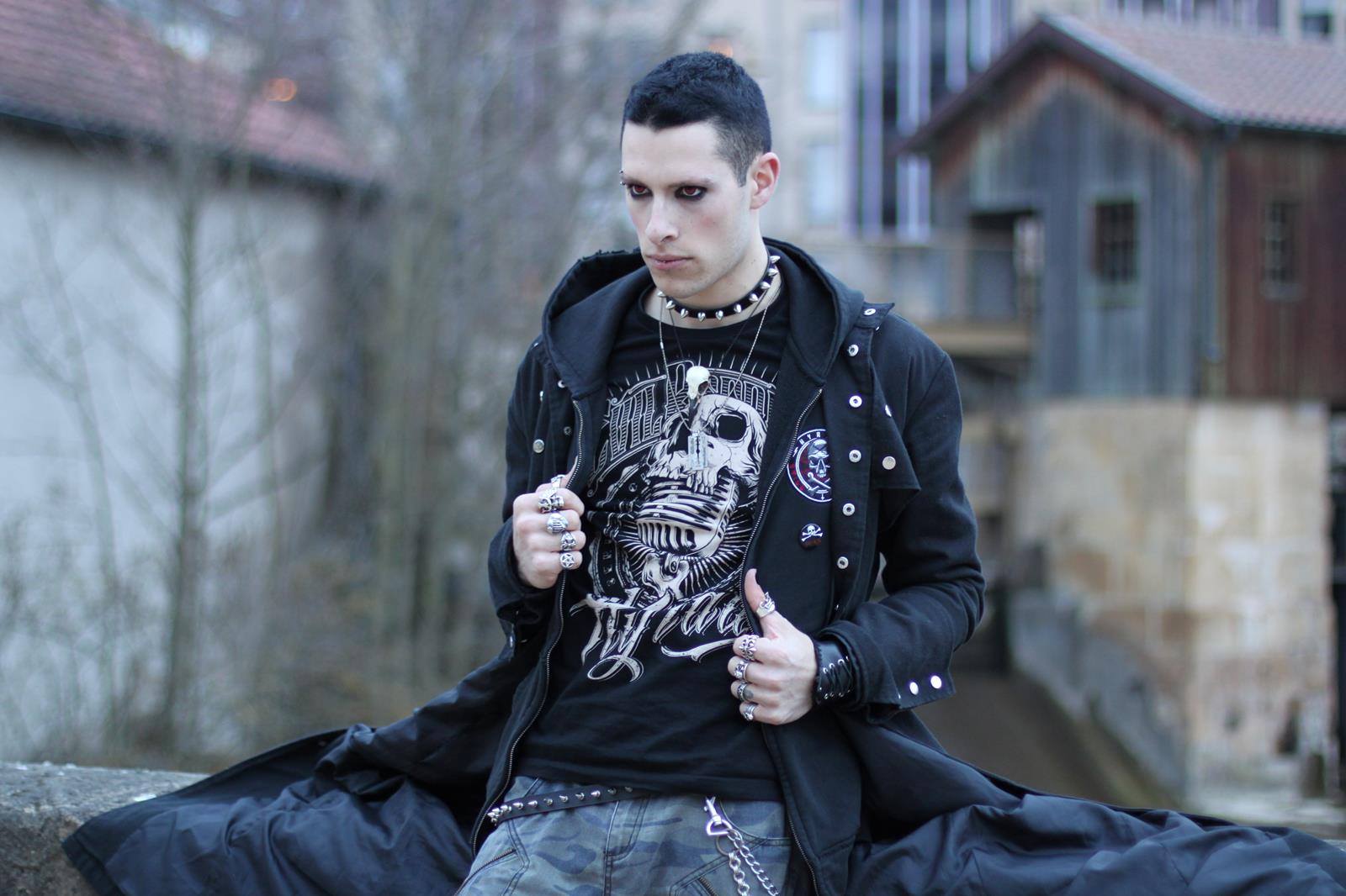 Gothic model guy at ren faire wearing a raven skull necklace and goth and punk biker style bird skull accessories.