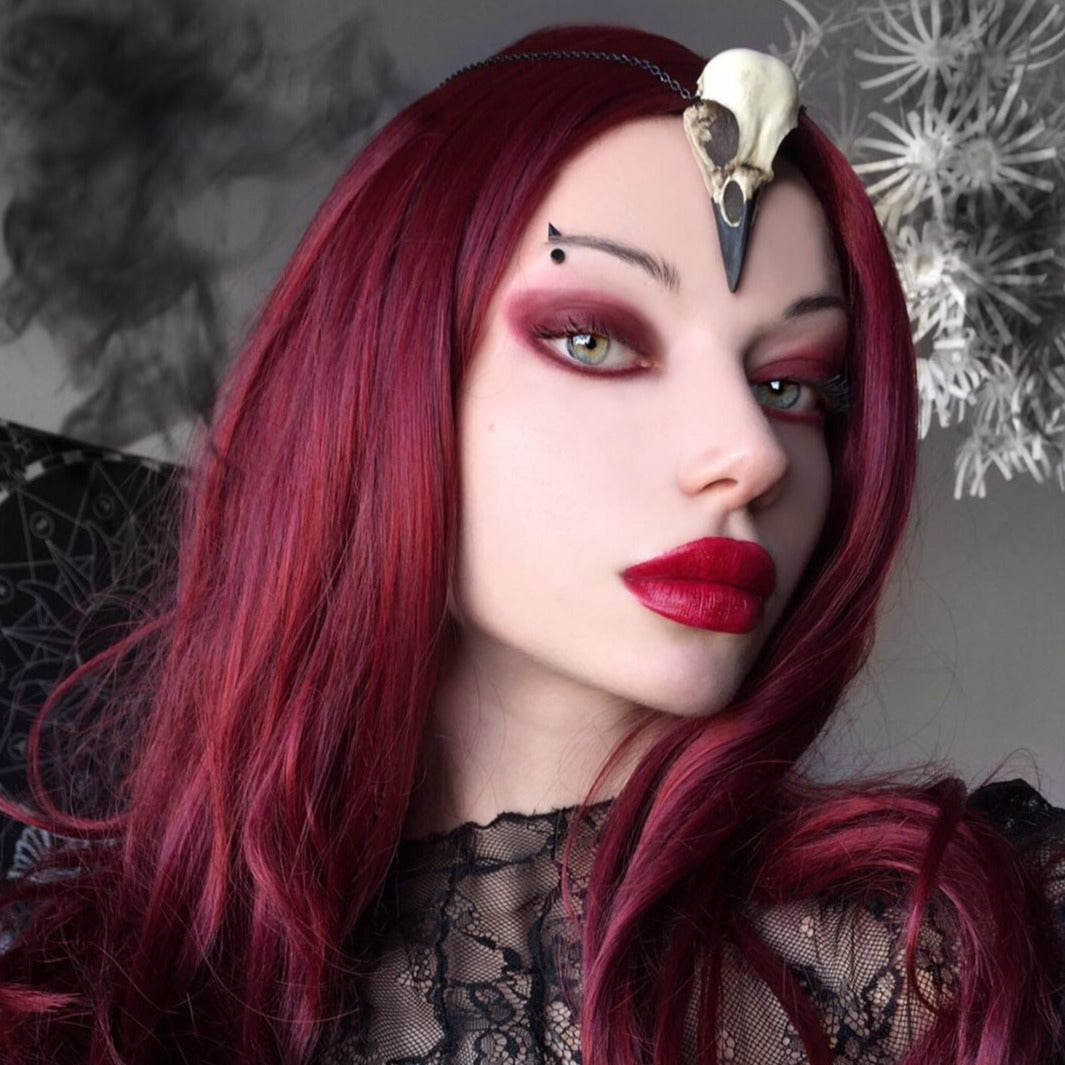 gothic alt model wearing a crow skull necklace bird skull jewelry for witchy gothic women, a creepy goth Halloween accessory.