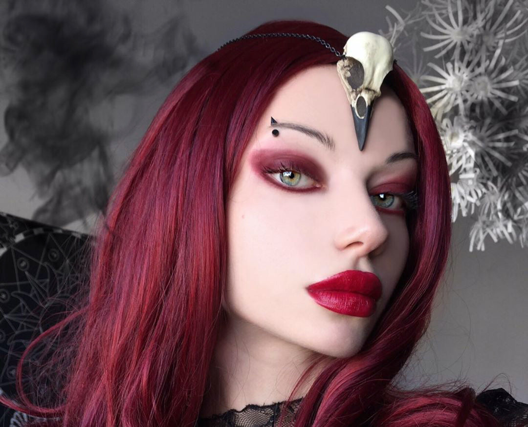 Close up of gothic alt model wearing a crow skull necklace bird skull jewelry for witchy gothic women, a creepy goth accessory.