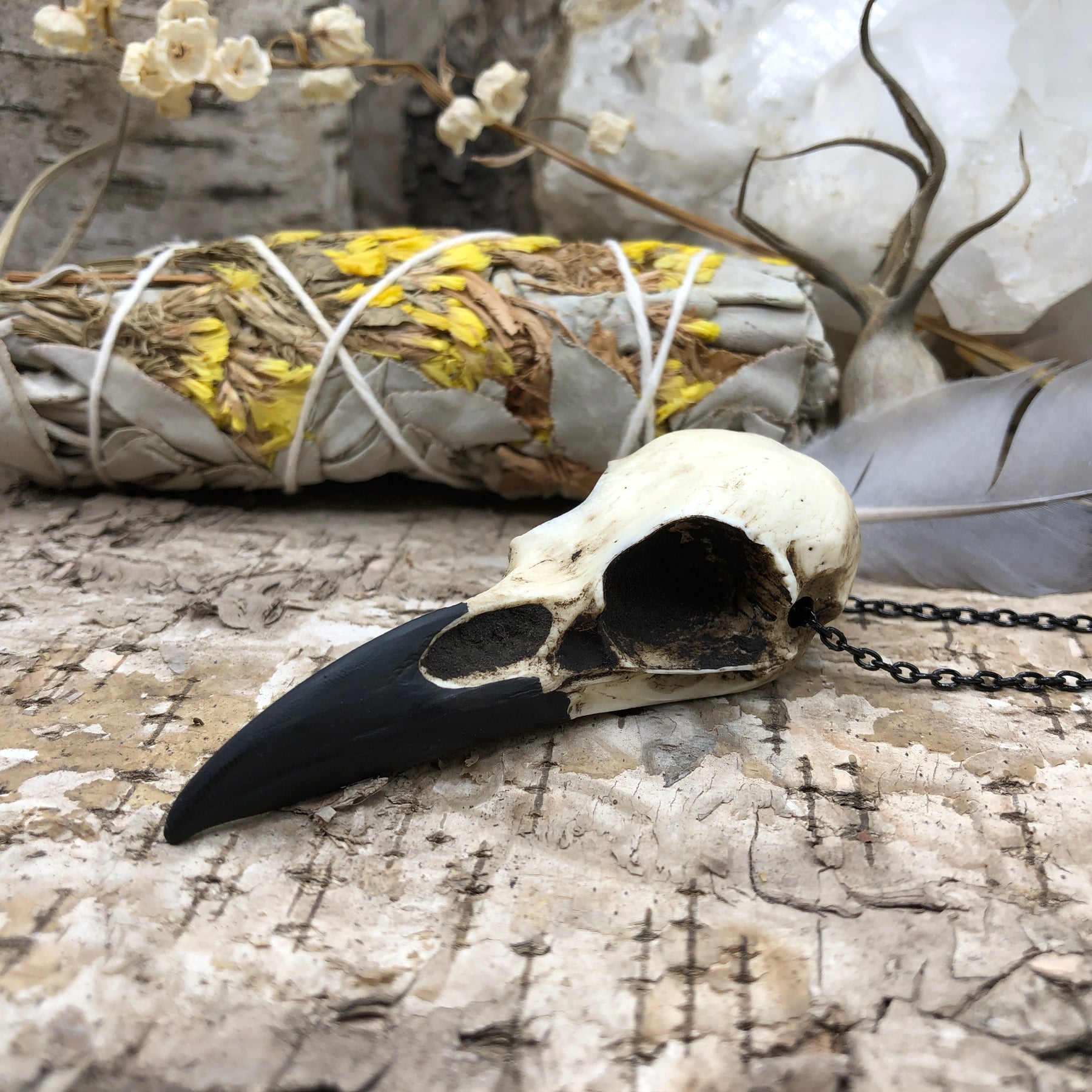 Side view of a handmade resin raven skull necklace bird skull bone jewelry pendant for gothic witchy style men or women.