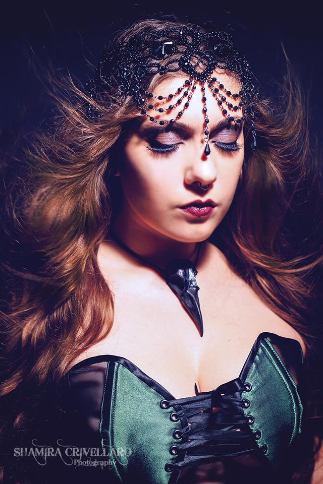 Gothic raven queen wearing large full size raven skull pendant bird skull jewelry and corset and black lace crown.