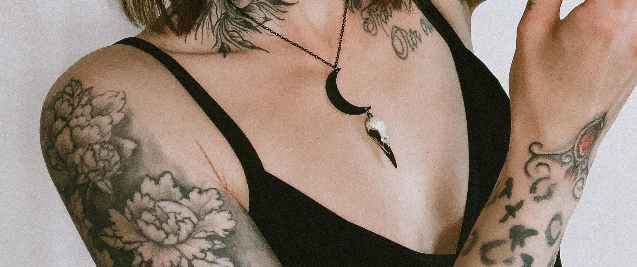 Goth model with tattoos wearing a lunar crescent moon raven skull necklace