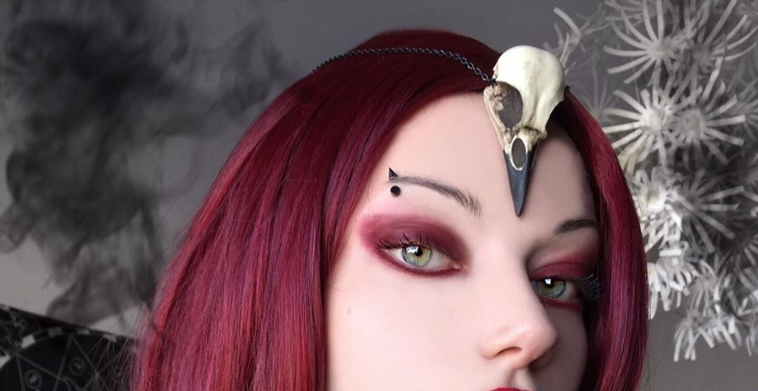 crow skull necklace being worn by gothic model in witchy goth style.
