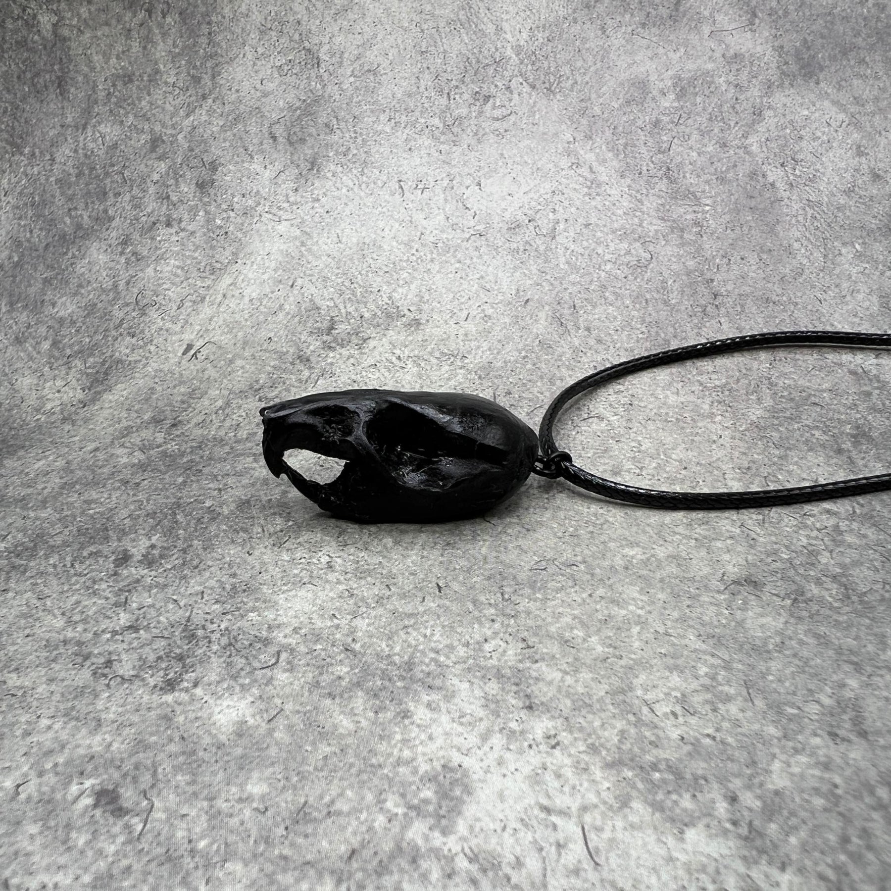 Left side view of a bone jewelry black resin rat skull necklace pendant for goths that love Halloween and taxidermy accessories.