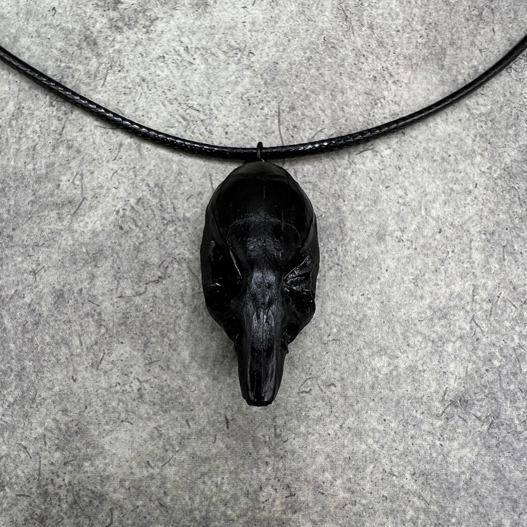 Front and top close up view of a bone jewelry black resin rat skull necklace pendant for goths that love Halloween and taxidermy accessories.