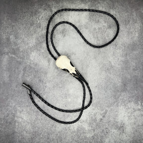 A raven skull western bolo tie also known as a bola tie, string tie, or cowboy tie with a resin bird skull and braided cord made by Raven Ranch Studio.