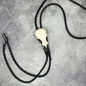 A raven skull western bolo tie also known as a bola tie, string tie, or cowboy tie with a resin bird skull and braided cord made by Raven Ranch Studio.