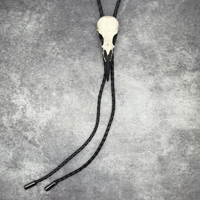 A raven skull western bolo tie also known as a bola tie, string tie, or cowboy tie with a resin bird skull and braided cord made by Raven Ranch Studio.