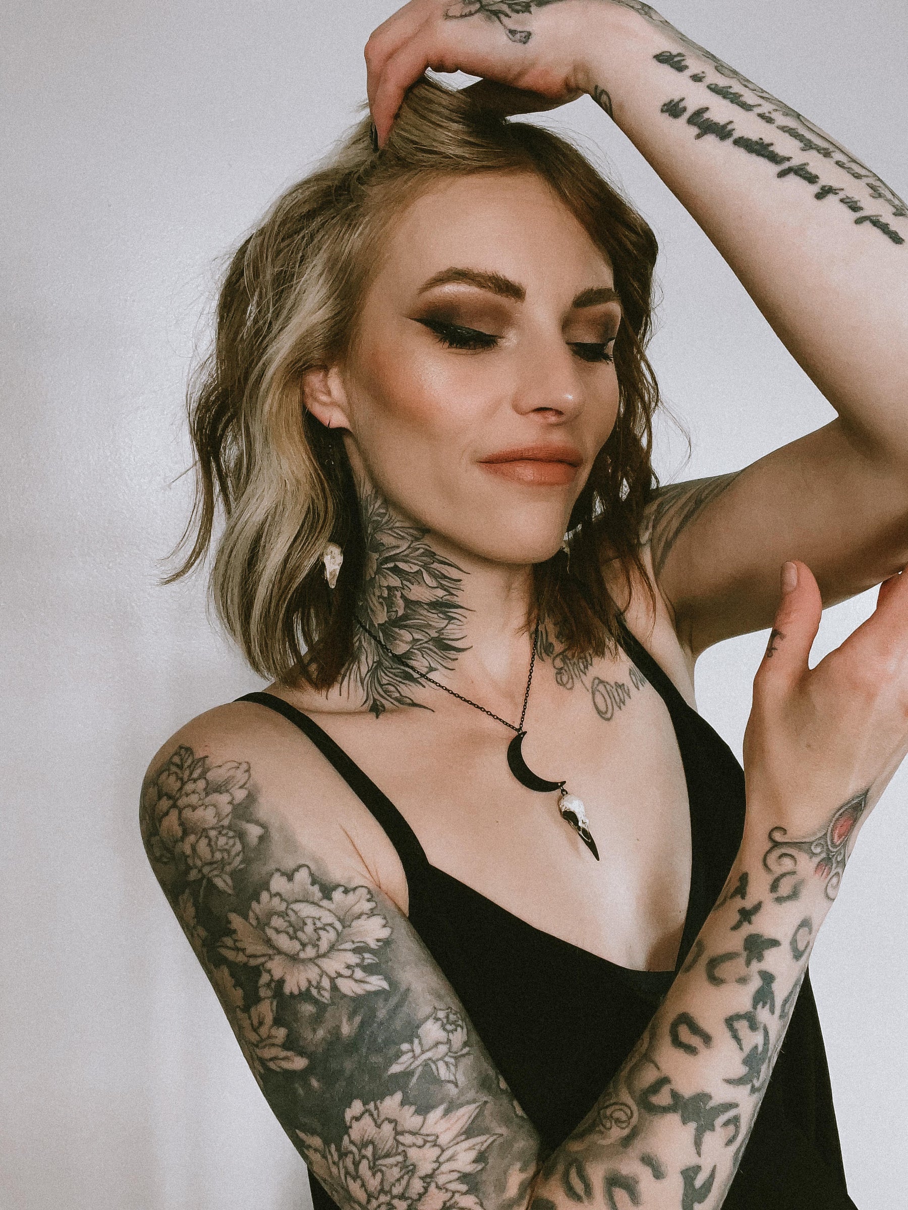 Alternative model tattooed girl wearing raven skull necklace lunar jewelry.