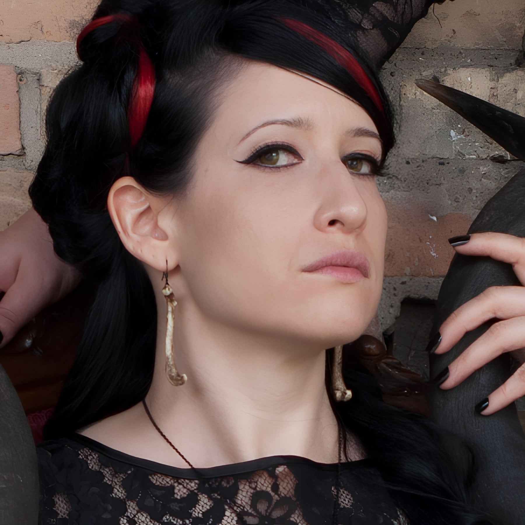 Alt model wearing resin femur bone dangle earrings that are handmade by Raven Ranch Studio, an expert resin skull artist.