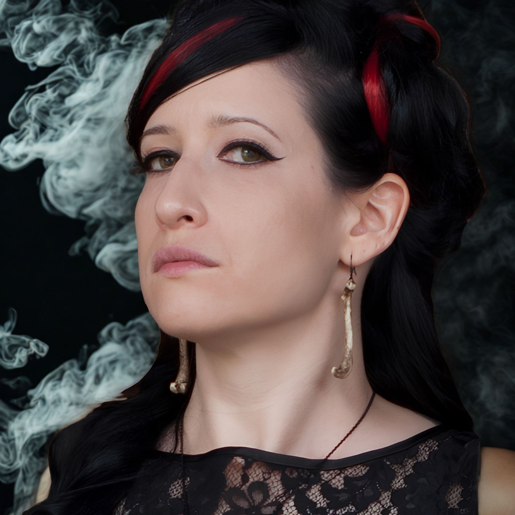 Alt model wearing resin femur bone dangle earrings that are handmade by Raven Ranch Studio, an expert resin skull artist.