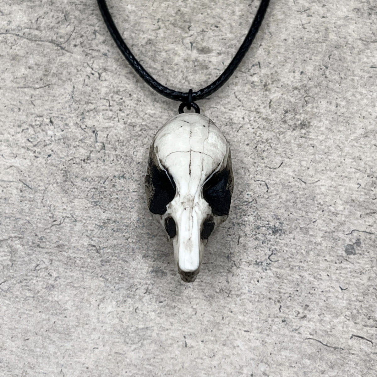 Front view of a bone jewelry aged patina resin rat skull necklace pendant for goths that love Halloween and taxidermy accessories.