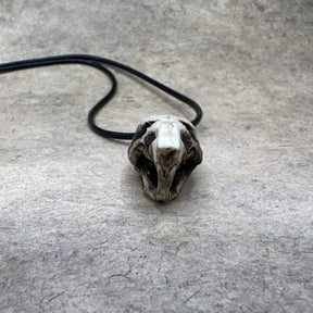 One bone jewelry aged patina resin rat skull necklace pendant for goths that love Halloween, placed next to a dime for size