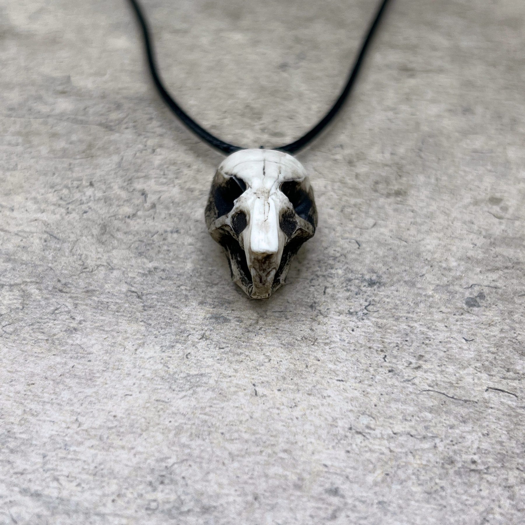 Close up view of a bone jewelry aged patina resin rat skull necklace pendant for goths that love Halloween and taxidermy accessories.