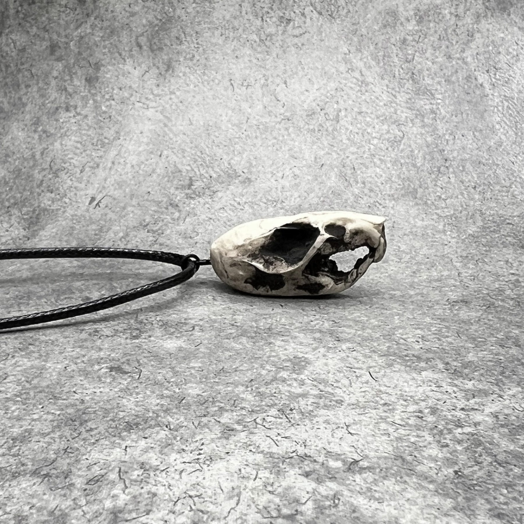 Right side view of a bone jewelry aged patina resin rat skull necklace pendant for goths that love Halloween and taxidermy accessories.