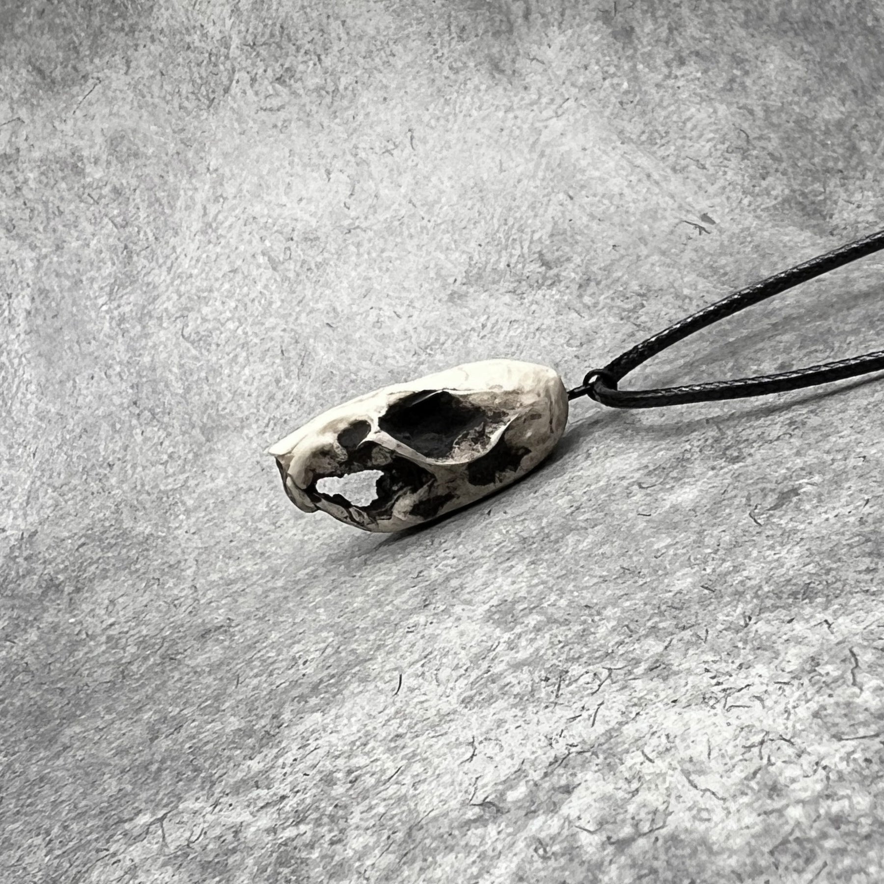 Left side view of a bone jewelry aged patina resin rat skull necklace pendant for goths that love Halloween and taxidermy accessories.