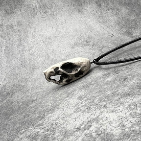 Left side view of a bone jewelry aged patina resin rat skull necklace pendant for goths that love Halloween and taxidermy accessories.
