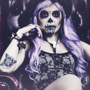 A life size resin raven skull necklace handmade by a skull jewelry artist and worn by gothic alt model. The style of the necklace is alternative and witchy for gothic fashion or Halloween. The bone jewelry pendant is brown with a black beak and looks like a real animal skull.