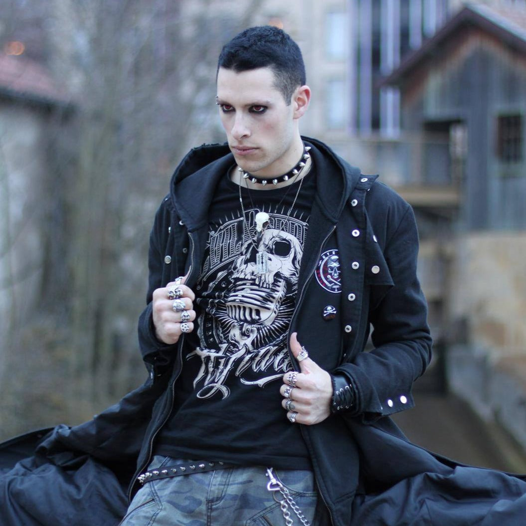 Goth punk man wearing a raven skull necklace and vampire eyes