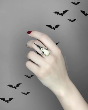 Gothic bird skull witchy style resin raven skull ring. A miniature raven skull ring that is a bird skull jewelry accessory for goths, ren faire, festivals and halloween costumes. The skull has a patina aged finish with black beak and is worn by a beautiful goth influencer model.