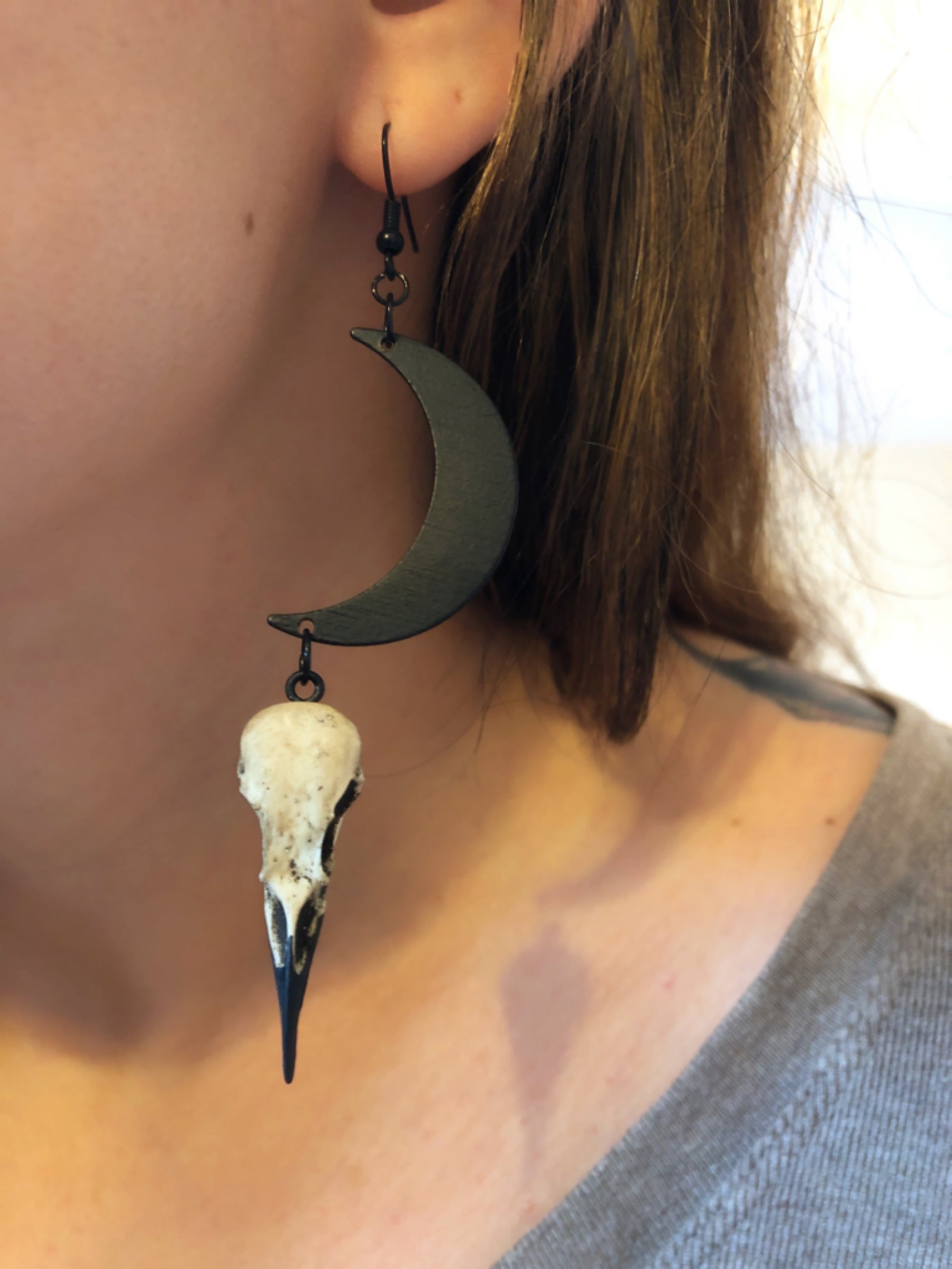 goth woman wearing gift idea Dangle earlobe raven goth skull charm earrings with crescent moons and resin bird skulls.