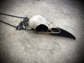 Side view of Gothic black death moth luna butterfly charm pendant and bone jewelry mini raven skull dangle pendant.