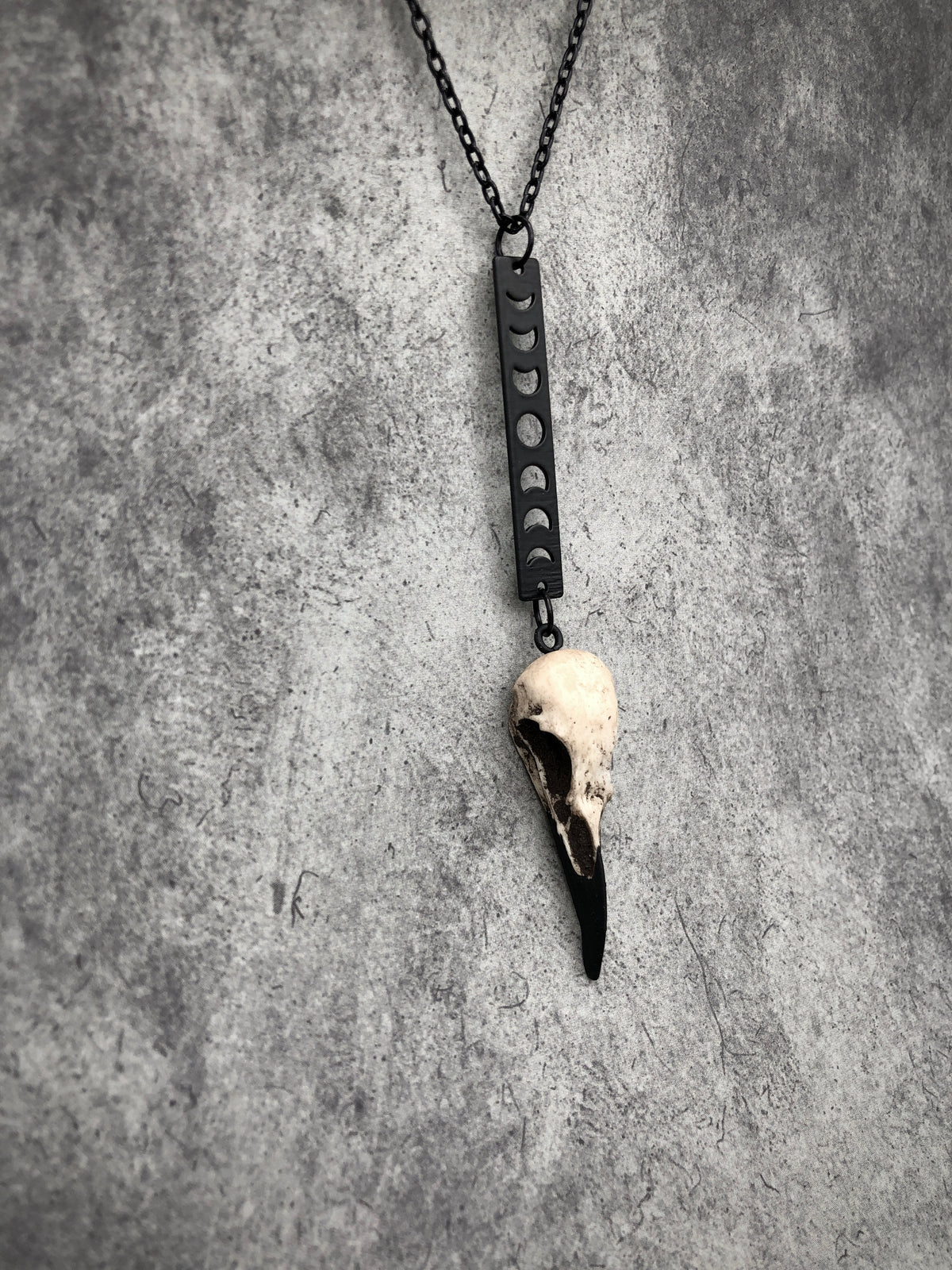 Side view of Moon phase vertical bar charm pendant and bone jewelry mini resin raven bird skull dangle pendant.