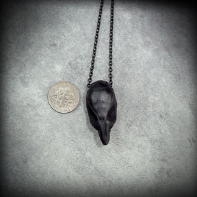 One bone jewelry black resin rat skull necklace pendant for goths that love Halloween, placed next to a dime for size