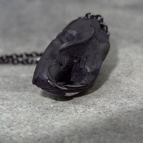 Close up view of a bone jewelry black resin rat skull necklace pendant for goths that love Halloween and taxidermy accessories.