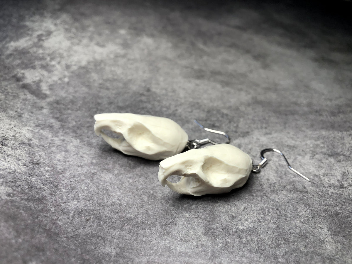 Top view of a bone jewelry resin rat skull dangle earrings for goths that love Halloween and taxidermy accessories.