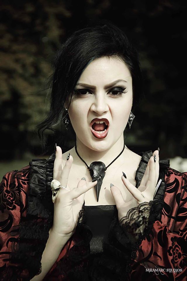 Vampire gothic girl with bone jewelry raven skull ring on her hand and a bird skull viking pendant around her neck.