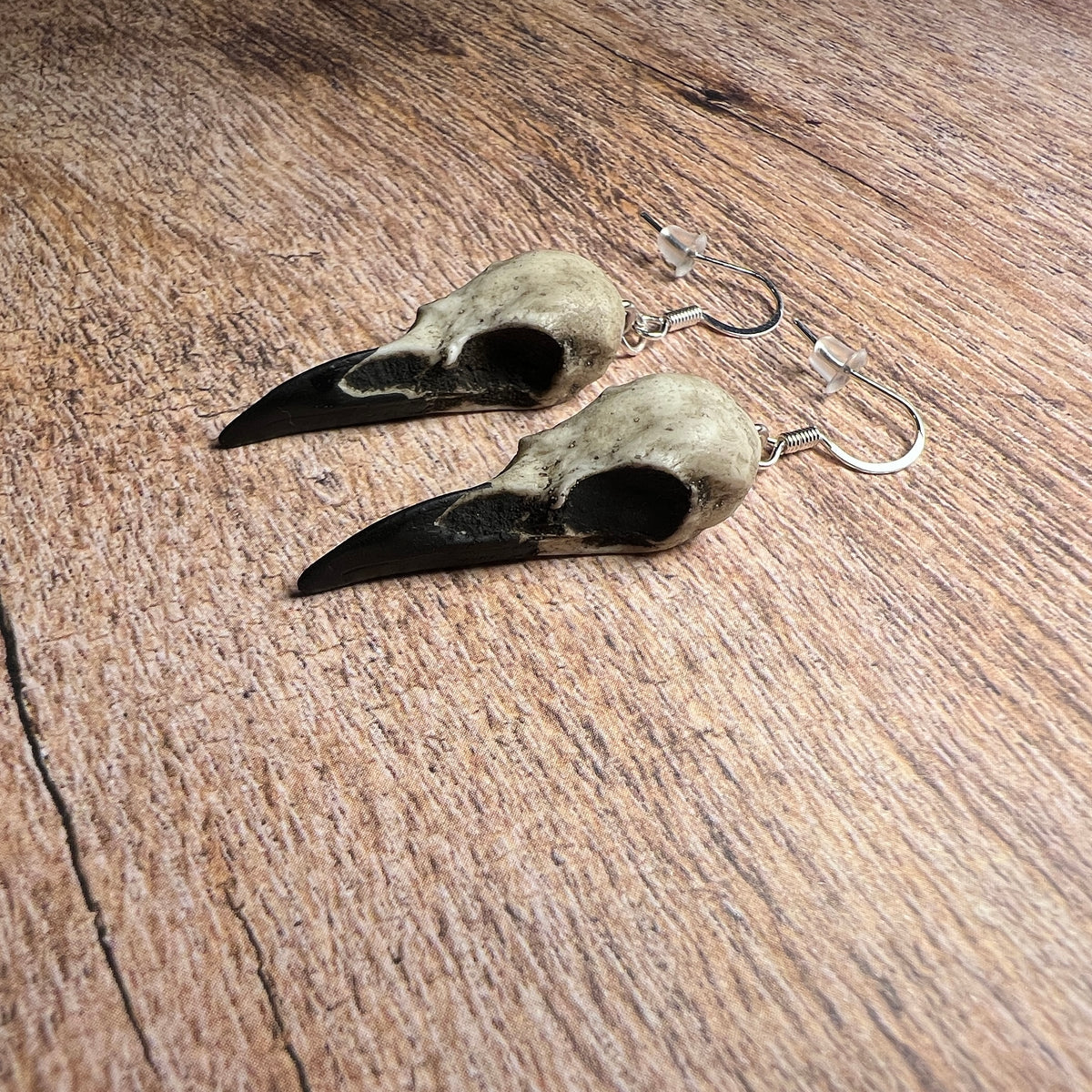 Side view of raven skull dangle earring bird skulls, mini charms tiny resin gothic woodland jewelry gift for women.